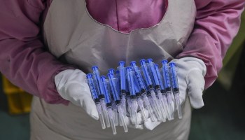 In this photograph taken on September 2, 2020, a worker displays syringes at the Hindustan Syringes factory in Faridabad.