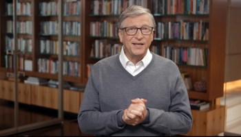 Bill Gates speaking in front of a wall of bookshelves.