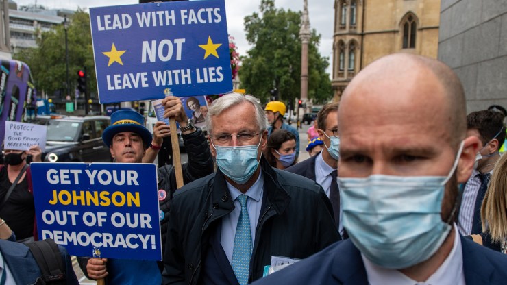 Michel Barnier, the EU's chief Brexit negotiator, arrives with members of his team for more Brexit trade talks on Sept. 9, in London, England, as anti-Brexit protesters follow him.