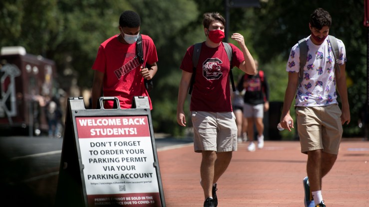 Three students wearing face masks walk on campus at the University of South Carolina on Sept. 3.