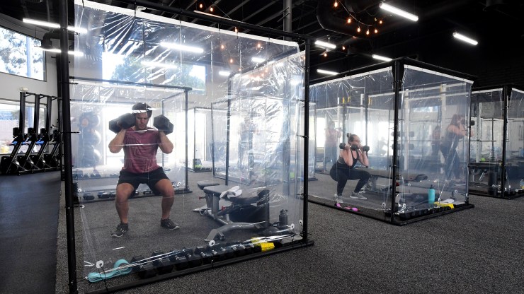 People exercise in workout pods surrounded by plastic sheets at a gym in Redondo Beach, California, in June.