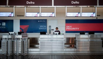 A Delta Air Lines employee waits for passengers at an empty check-in counter at Ronald Reagan Washington National Airport in Arlington, Virginia.