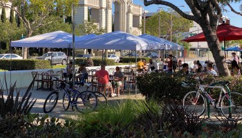 People enjoy a newly added outdoor dining area created by the city partially blocking a main boulevard.