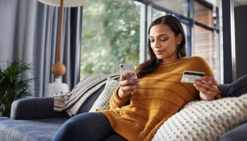 A woman uses her credit card to make an online purchase via her phone. States are collecting substantial online sales tax revenue while some other forms of commerce shrink.