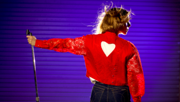 René Kladzyk performs a song, wearing a red jacket with a heart on the back.