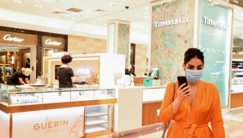 A customer wearing a face mask walks past shops of luxury brands Tiffany and Guerin at the Galeries Lafayette in May in Paris, France.