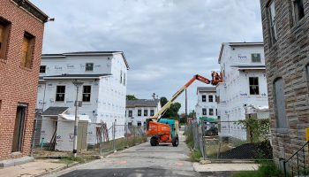 A new low-income rental development rises down the street from where Black Women Build - Baltimore is renovating houses for homeownership,