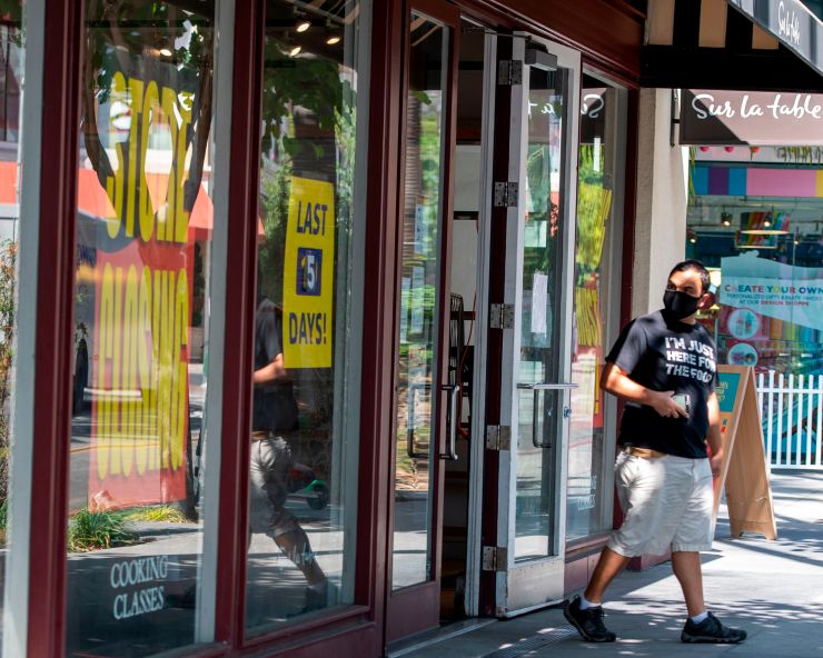 "Store Closing" signs are posted at a "Sur La Table" kitchenware store as people walk by on Sept. 22 in Los Angeles.