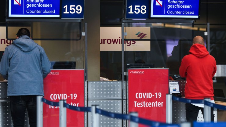 Travelers stand at an information desk to ask about the free-of-charge COVID-19 testing station at Düsseldorf International Airport on October 19, 2020.