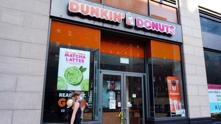 A person in a protective mask walks by a temporarily closed Dunkin' Donuts as New York City moves into Phase 3 of reopening following restrictions imposed to curb the coronavirus pandemic on July 13, 2020.