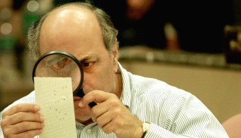 Judge Robert Rosenberg of the Broward County Canvassing Board uses a magnifying glass to examine a dimpled chad on a punch card ballot November 24, 2000 during a vote recount in Fort Lauderdale, Florida.