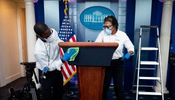 Cleaning staff disinfect the lectern in the White House pressroom in April.