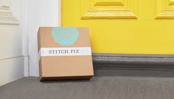 A stitch Fix box delivered at the doorstep of a house with a yellow door.