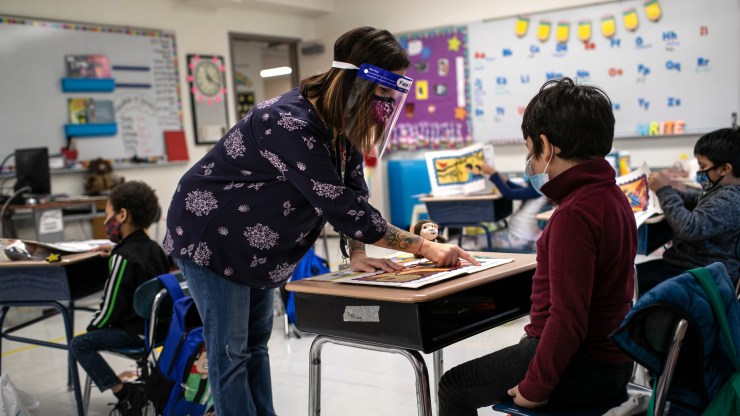 A teacher wearing a face mask and face shield helps her first grade student during in-person class at an elementary school in Stamford, Connecticut, on Sept. 16.