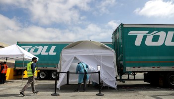 A worker walks toward a tent to be tested for COVID-19 at a site provided for port truck drivers and warehouse workers in Long Beach, California.