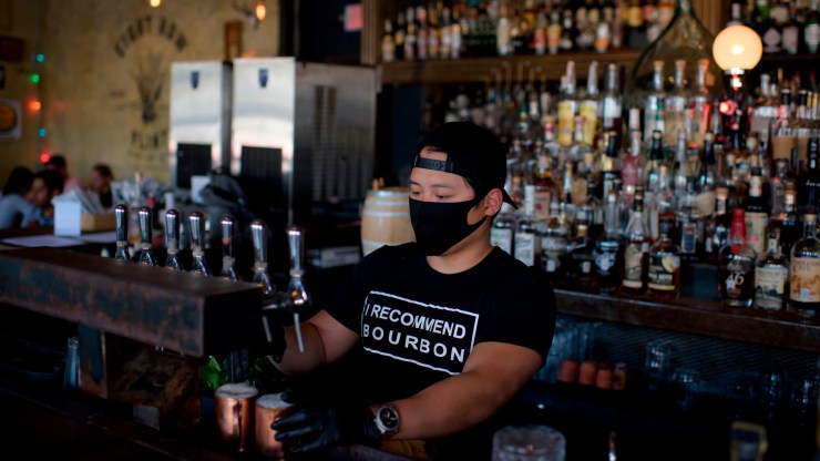 A bartender wearing a facemask and gloves makes drinks at Eight Row Flint in Houston, Texas.