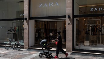 A woman wearing sweatpants and a face mask pushes a stroller past a Zara store in Bergamo, Italy, in June.