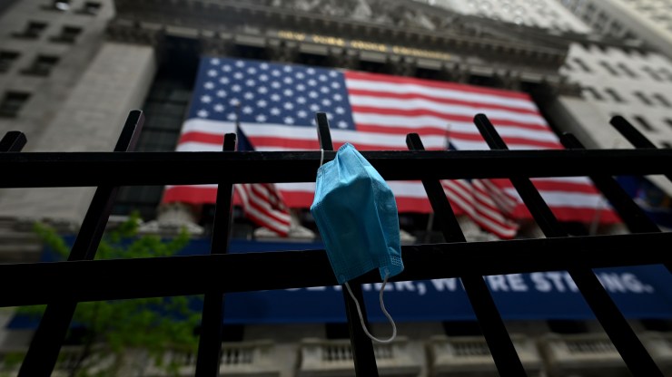 A face mask hangs on a fence post in front of the New York Stock Exchange in May.