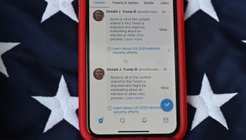 This illustration photo shows a mobile phone placed on an American flag with tweets from President Donald Trump masked with warnings imposed by Twitter stating that they may be incorrect, November 5, 2020, as presidential election vote counting continues.