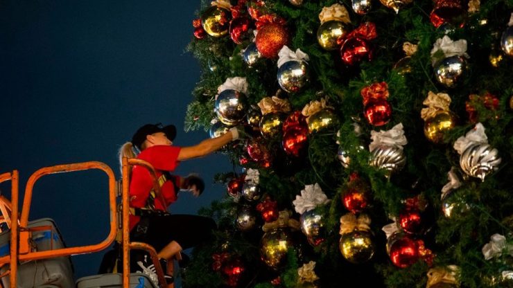 A worker decorates the Christmas tree at The Grove outdoor shopping center in Los Angeles on, November 5, 2020.