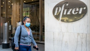 People walk by the Pfizer headquarters on November 9, 2020 in New York City. Pharmaceutical company Pfizer announced positive early results on its COVID-19 vaccine trial, which has proven to be 90% effective in preventing infection.