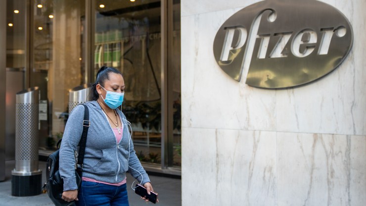 People walk by the Pfizer headquarters on November 9, 2020 in New York City. Pharmaceutical company Pfizer announced positive early results on its COVID-19 vaccine trial, which has proven to be 90% effective in preventing infection.