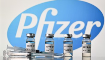 An illustration picture shows vials with COVID-19 Vaccine stickers attached and syringes with the logo of pharmaceutical company Pfizer, on November 17, 2020.