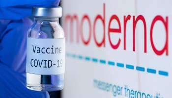 This picture taken on November 18, 2020 shows a bottle reading "Vaccine COVID-19" next to the Moderna biotech company logo.