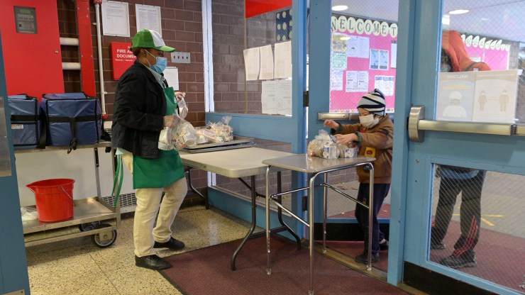 A student chaperoned by an adult picks up a meal to go on November 19, 2020 at Yung Wing School P.S. 124 in New York City.
