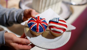 A member of staff at the Hummingbird Bakery poses with cupcakes themed with icing depicting the Union Flag and the American flag to mark the Royal Wedding of Prince Harry and Meghan Markle in central London on May 11, 2018.