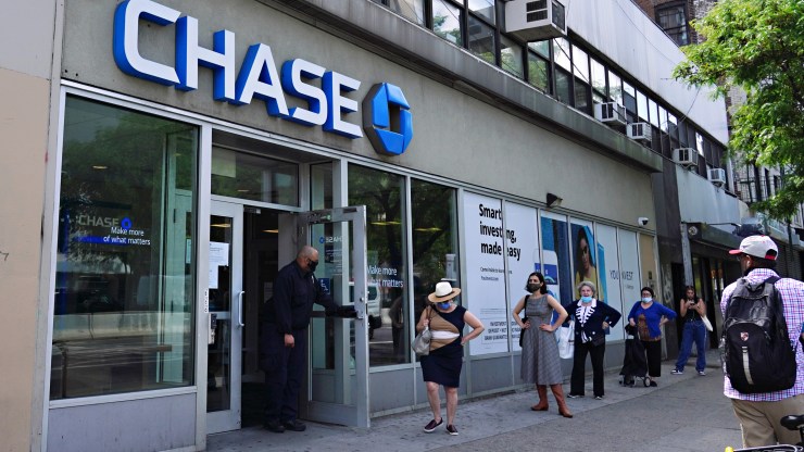 People wait to use an ATM outside a Chase branch in New York City. Interest on savings has dropped since last year.