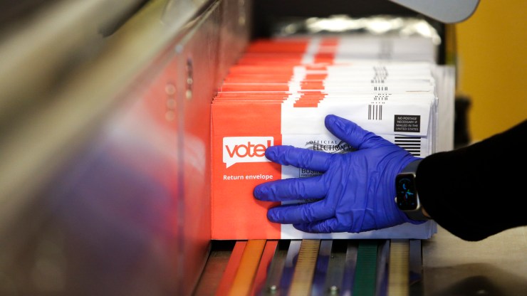 Election workers load ballots into a sorting machine on Election Day at the King County Elections office in Renton, Washington.