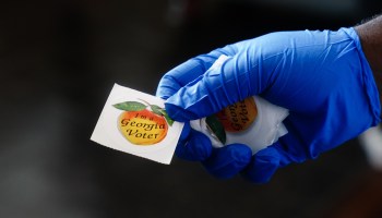 A polling place worker holds an "I'm a Georgia Voter" sticker to hand to a voter on June 9, 2020, in Atlanta, Georgia.