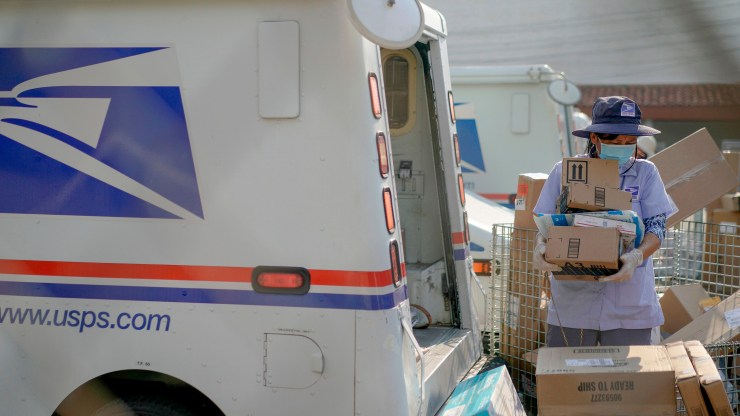 A postal worker loads packages into her truck outside a USPS center in Los Angeles, California, in August.
