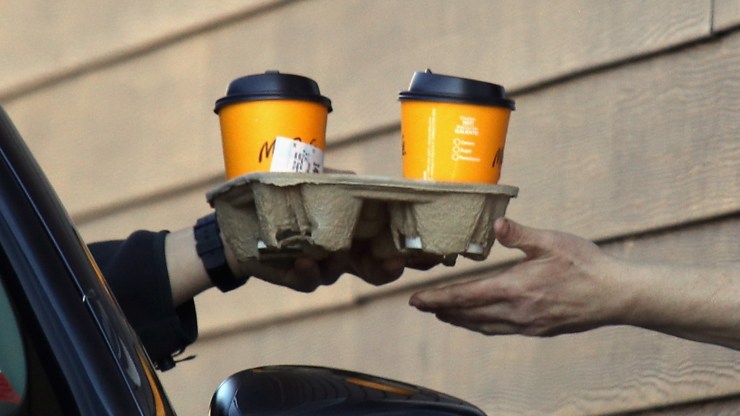 A worker hands a customer a tray holding two coffees at a McDonald's drive-thru in Plainview, New York, in March.
