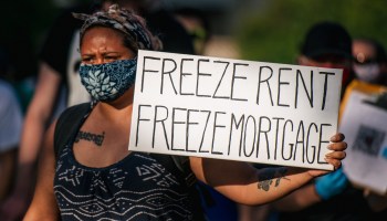 A woman holds a sign reading "freeze rent, freeze mortgage" as demonstrators march in the street during the Cancel Rent and Mortgages rally on June 30, 2020 in Minneapolis, Minnesota.