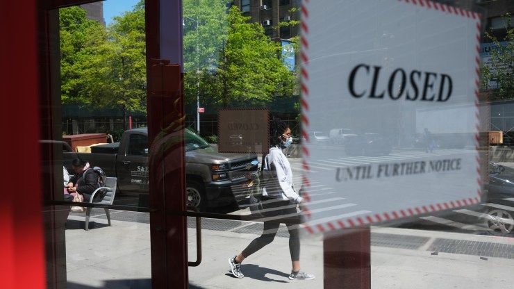 A woman walks through a shuttered business district in Brooklyn on May 12, 2020 in New York City.