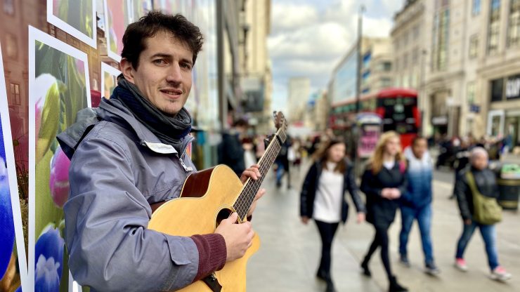 Folk singer David Fisher holds his guitar on the streets of London.