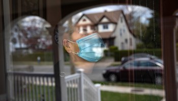 A woman looks out from her front door while she quarantines at home this April in Long Island, New York.