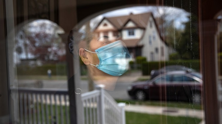 A woman looks out from her front door while she quarantines at home this April in Long Island, New York.