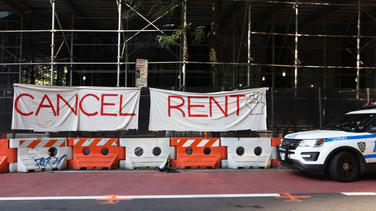 A NYPD vehicle parks in front of a "Cancel Rent" banner hung up by participants of a 'Resist Evictions' rally to protest evictions on August 10, 2020, in New York City.