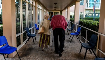 Two residents, seen from behind, walk inside a retirement community in Pompano Beach, Florida, earlier this year.