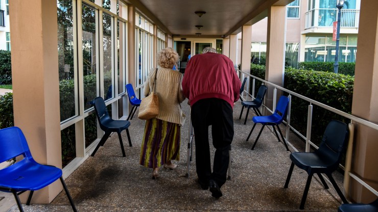 Two residents, seen from behind, walk inside a retirement community in Pompano Beach, Florida, earlier this year.