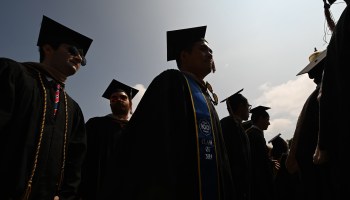 Students wearing academic regalia attend their graduation ceremony.