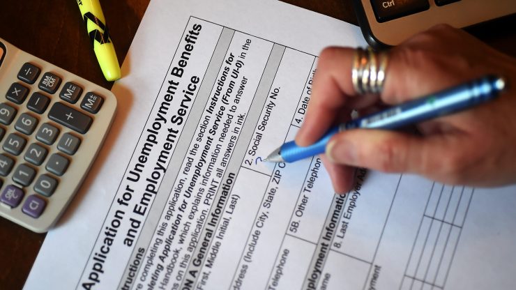 In this photo illustration, a person files an application for unemployment benefits