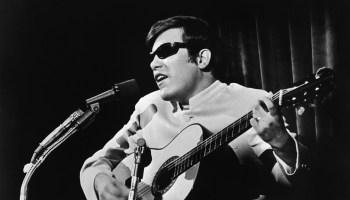 Puerto Rican singer and musician Jose Feliciano performs with a guitar in front of a microphone, late 1960s or early 1970s.