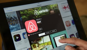 A woman browses the Airbnb app on a tablet.