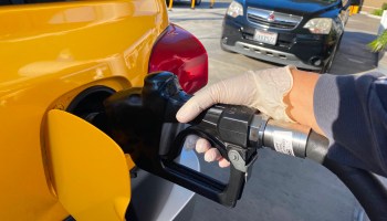 A woman wearing a glove fills her gas tank at a Los Angeles gas station in March.