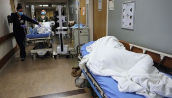 A patient lies on a stretcher in the hallway of the overloaded emergency room at a hospital in Southern California on Dec. 23.