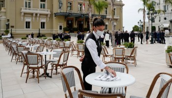 A waiter wearing a protective face mask sets a table on the terrace at the Cafe de Paris as restaurants and cafes reopen in Monaco in June.